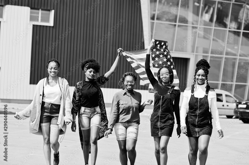 Group of five african american woman walking together on parking with USA flag.