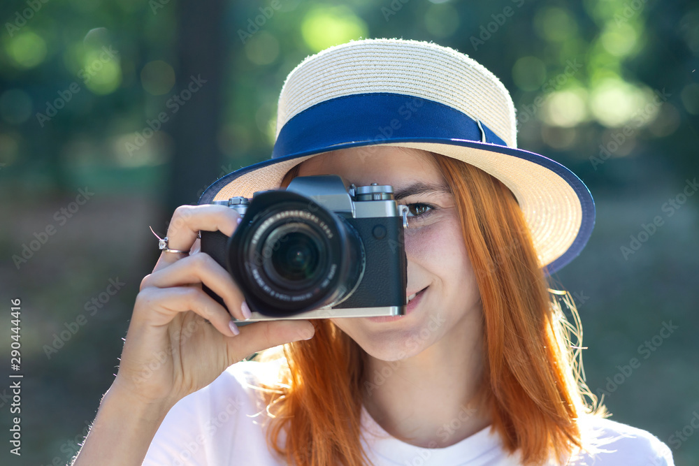 Pretty teenage girl with red hair taking picture with photo camera in summer park. Pretty teenage girl with red hair taking picture with photo camera in summer park.