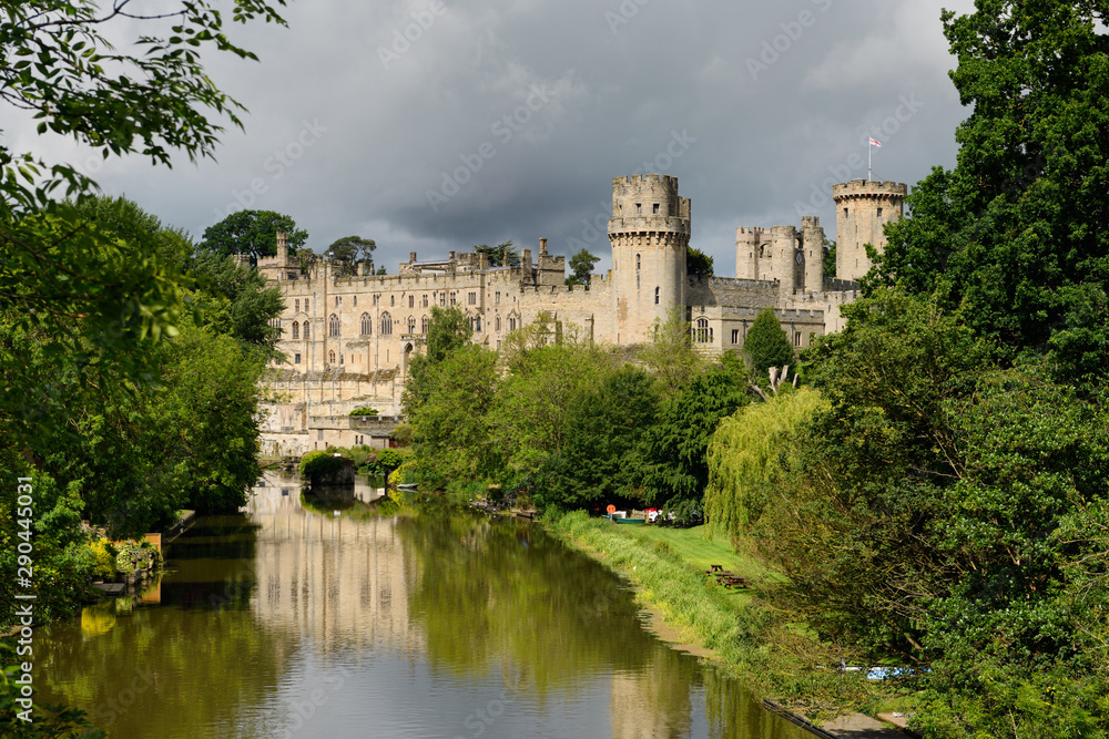 Medieval Warwick castle Great Hall and Ceasar's Tower reflected in the River Avon in Warwick England with dark clouds