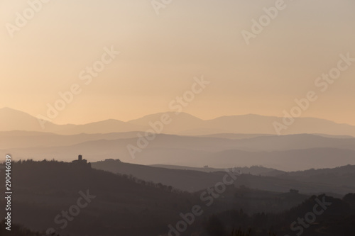 Beautiful view of Tuscany hills at sunset, with mist and warm colors © Massimo