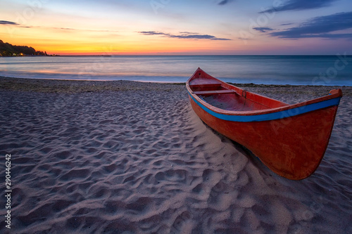 beauty morning with the lonely red boat on the sea beach