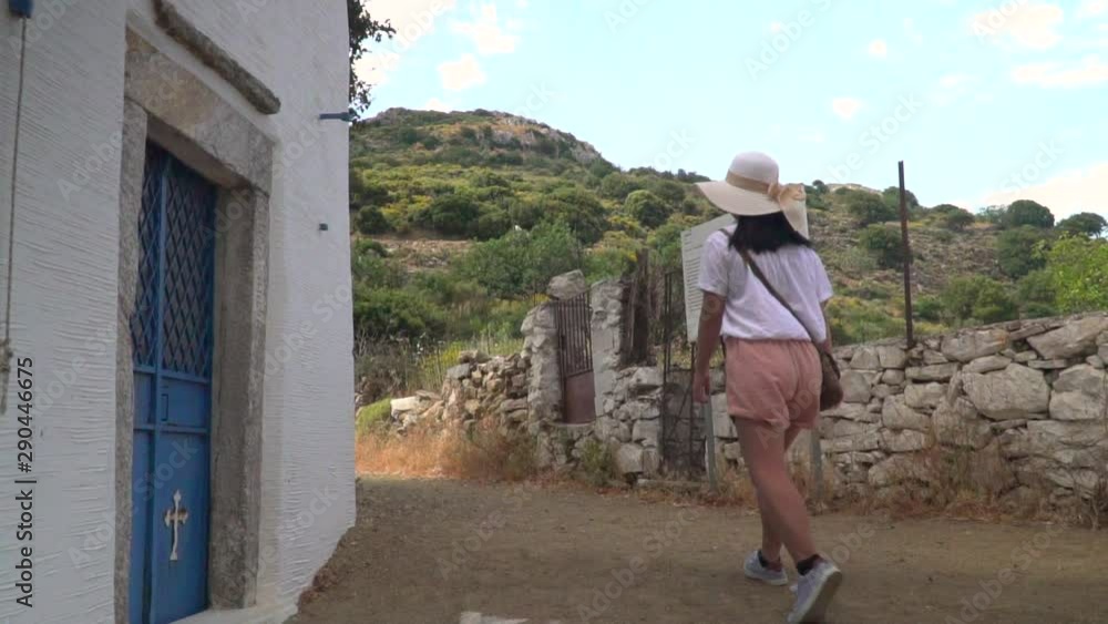 Low angle sliding shot from building to path with girl in hiking outfit walking through frame towards hills Low angle sliding shot from building to path with girl in hiking outfit walking through frame towards hills