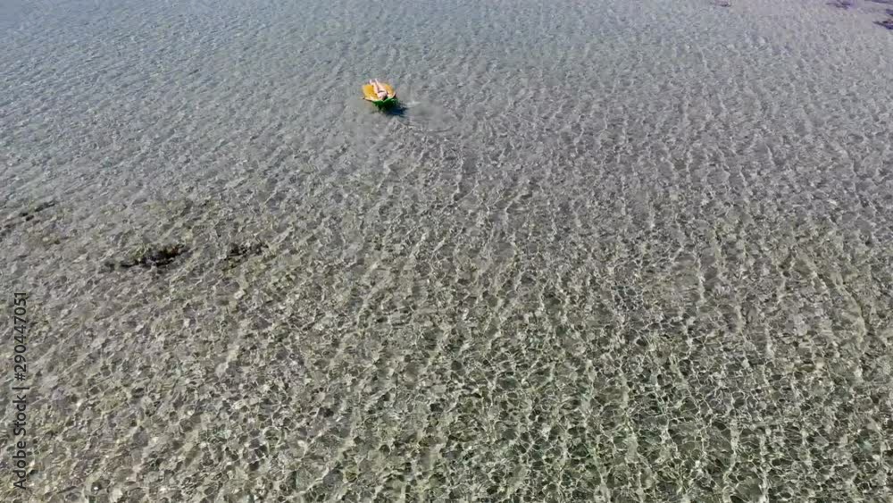 Girl relaxing on inflatable pineapple enjoying vacations. Inflatable mattress pineapple toy in seawater from above. Girl relaxing on inflatable pineapple enjoying vacations. Inflatable mattress pineapple toy in seawater from above.