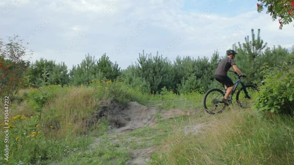 Mountain biker goes up a rugged mountain incline outdoors in the summer. Mountain biker goes up a rugged mountain incline outdoors in the summer.