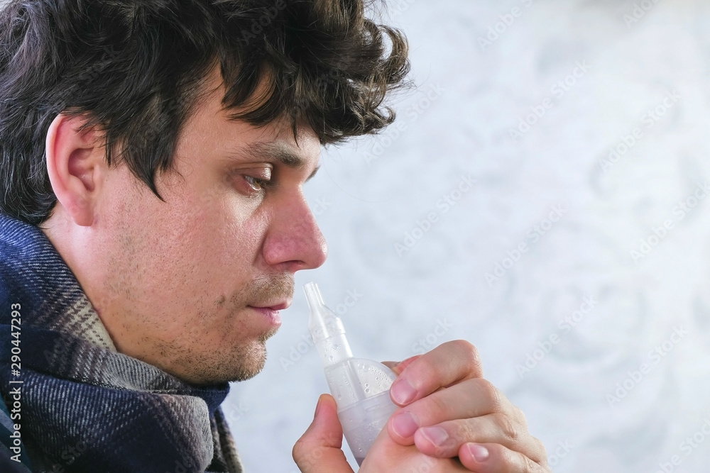 Sick man inhaling through inhaler nozzle for nose. Close-up face. Use ...
