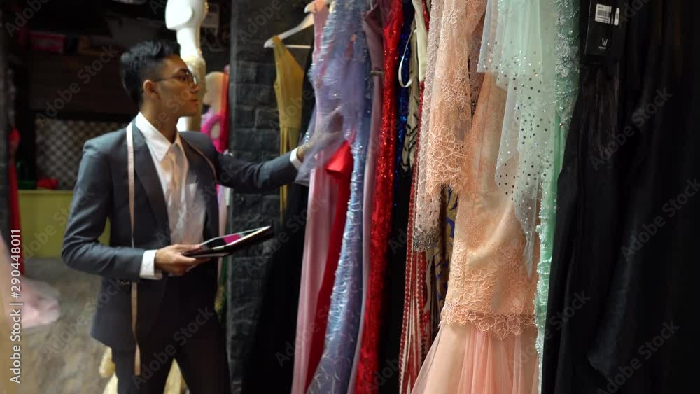 Manager of a formal gown boutique accounts for his inventory on a smart tablet Manager of a formal gown boutique accounts for his inventory on a smart tablet