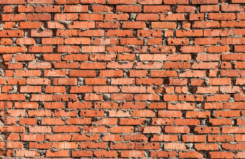 Naklejka premium Old rustic dirty uneven damaged red brick wall with gray cement seam. Abstract modern trendy texture background