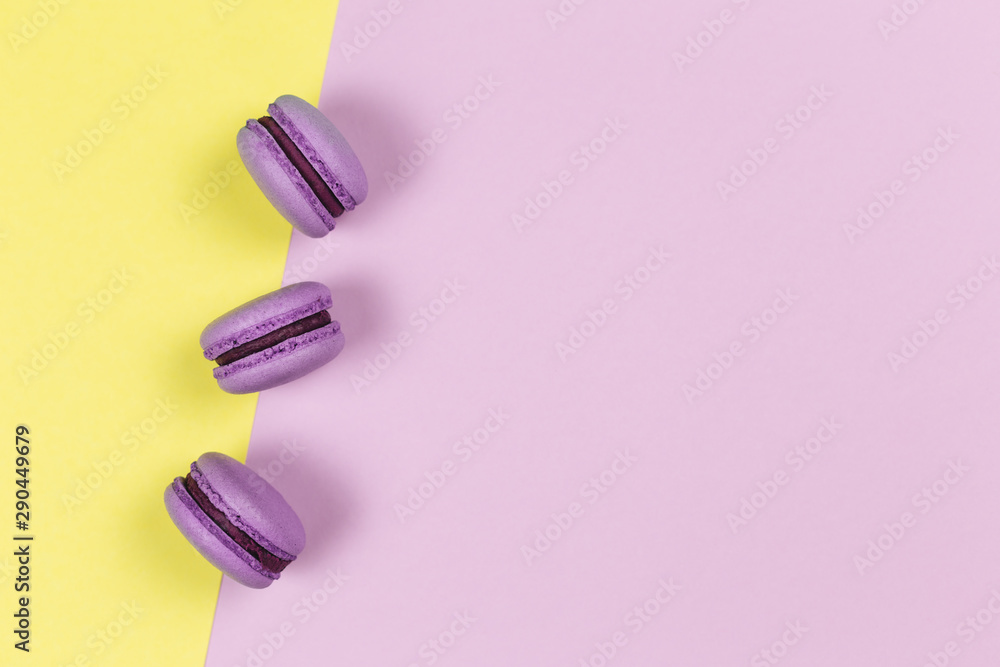 Three french macarons on a yellow and purple background. Place for text. Three french macarons on a yellow and purple background. Place for text.