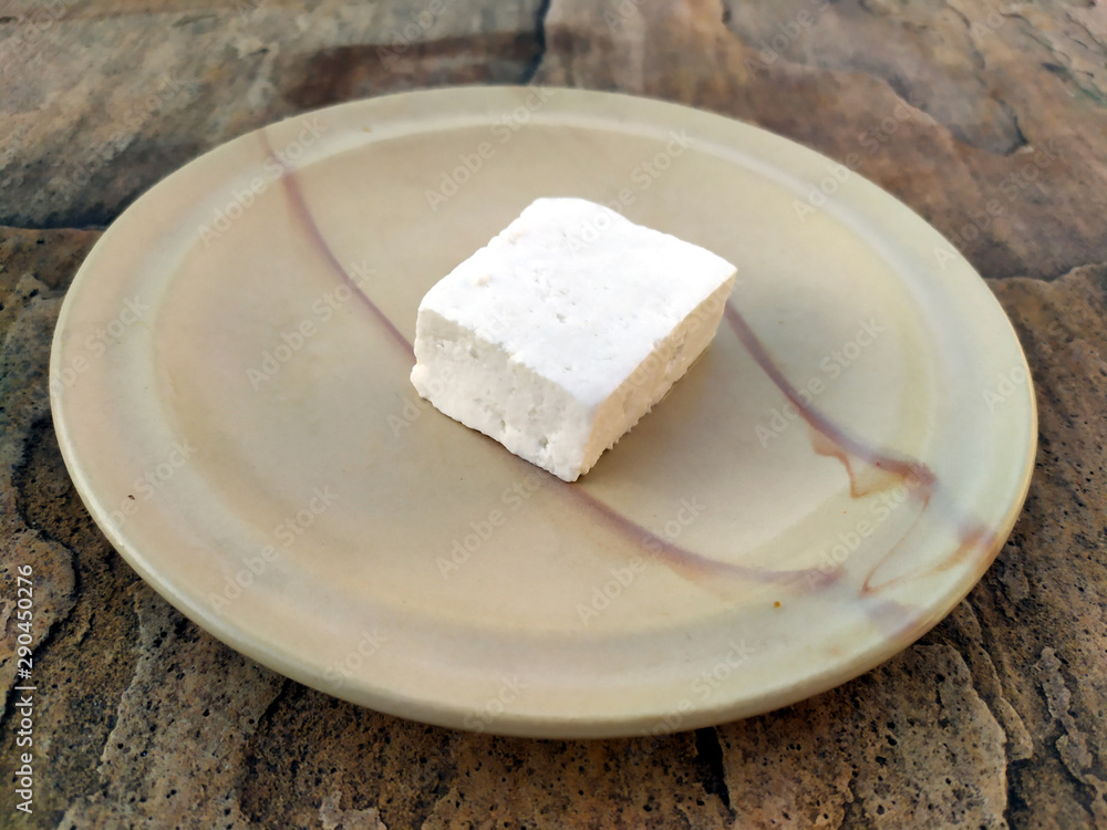 fresh cheese slice put in a plate isolated on stone background
