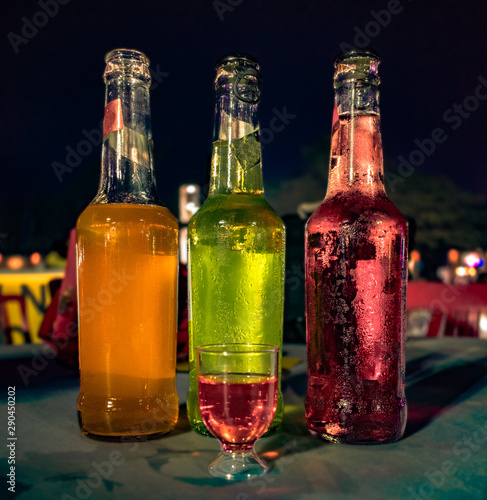 Three bottles of different colored Wines placed adjacent to each other with a small glass filled with red wine for tasting at a Wine Tasting Festival. photo