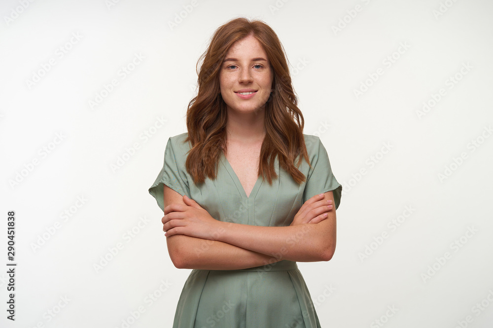 Attractive young red haired female with romantic hairstyle wearing vintage dress, keeping hands crossed on her chest and looking positively to camera, isolated over white background Attractive young red haired female with romantic hairstyle wearing vintage dress, keeping hands crossed on her chest and looking positively to camera, isolated over white background
