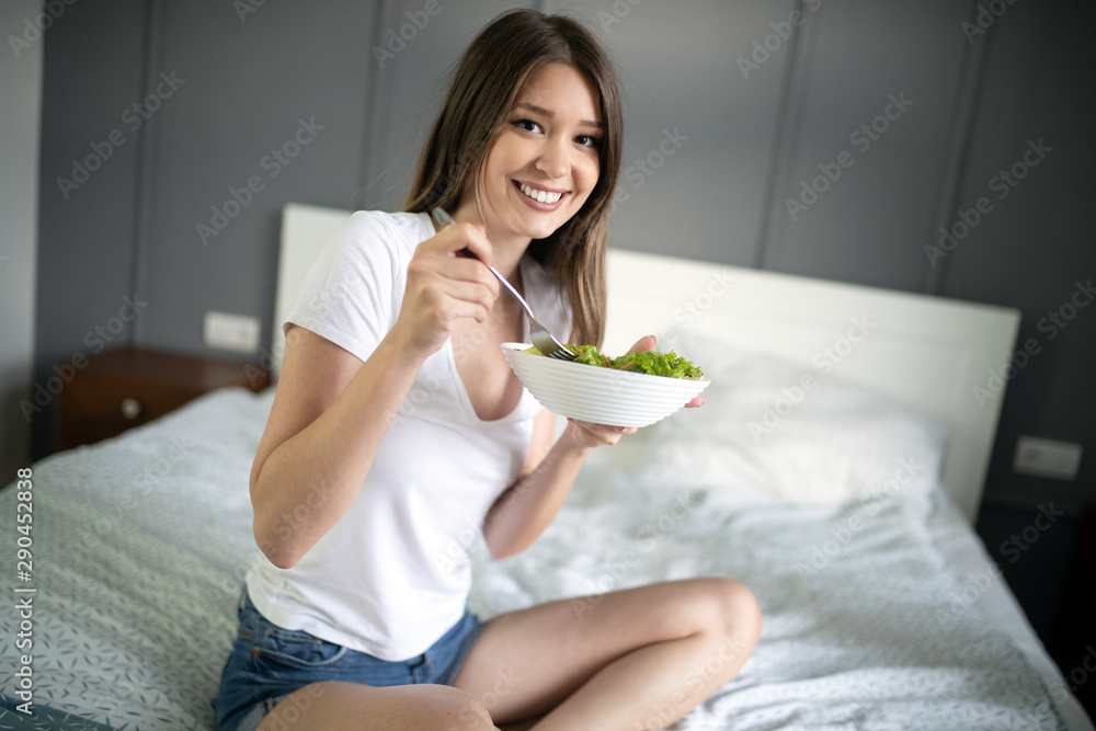 Young woman eating healthy salad after working out at home Young woman eating healthy salad after working out at home