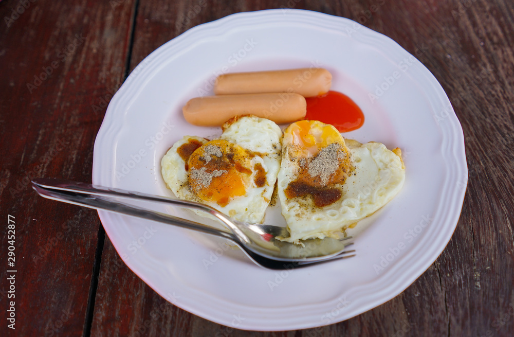 Boiled sausage and Fried eggs with white dish on the wood table Boiled sausage and Fried eggs with white dish on the wood table