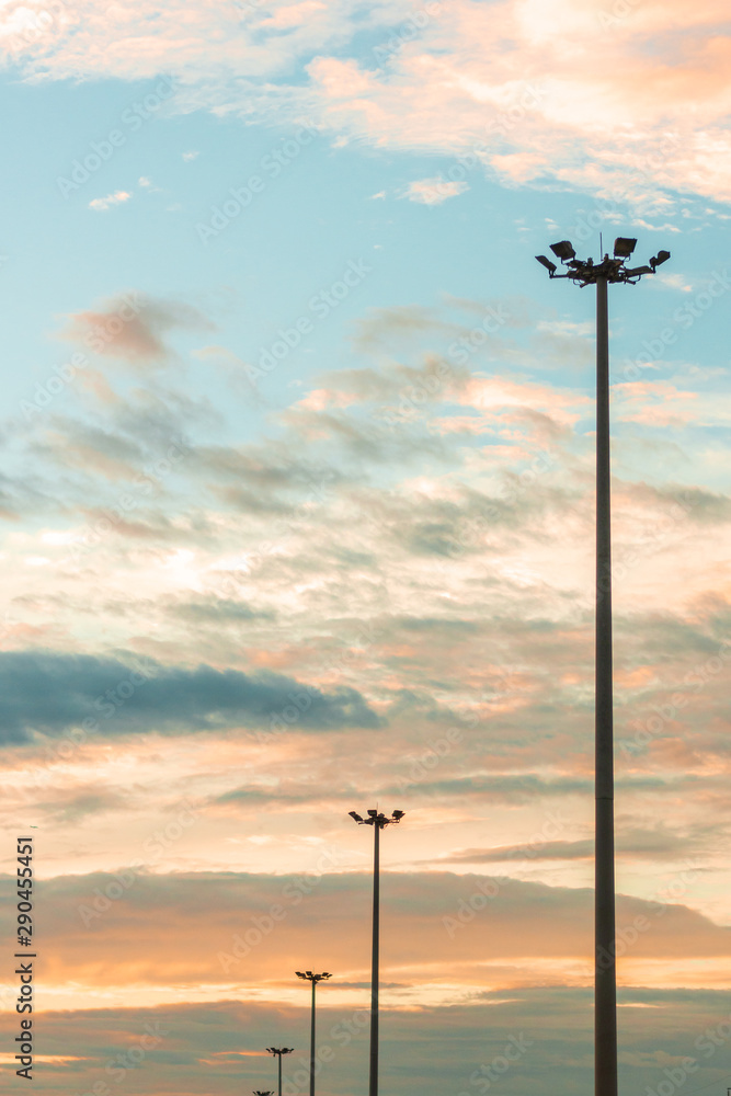Obraz premium Highway light pole against the blue sky and clouds at sunset.