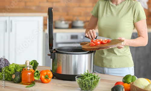 Woman using modern multi cooker in kitchen photo