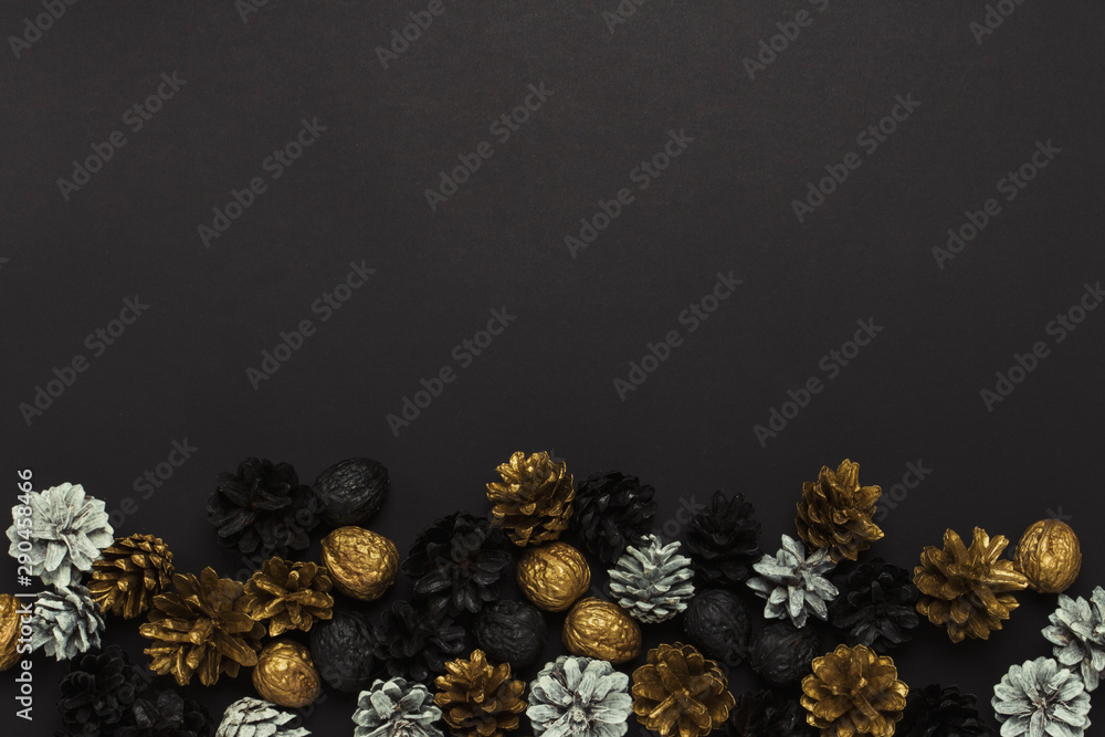 Pine cones and nuts painted in golden, black, white colors on a black background. Concept of Happy New Year and Merry Christmas. Flat lay, top view Pine cones and nuts painted in golden, black, white colors on a black background. Concept of Happy New Year and Merry Christmas. Flat lay, top view