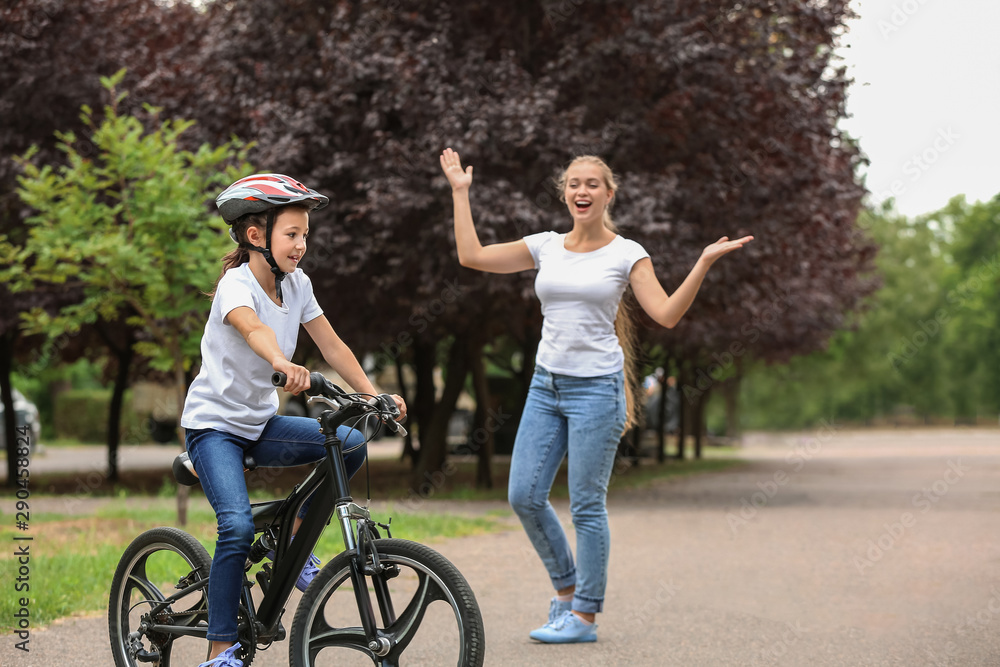 Mother proud of her daughter who learned to ride bicycle outdoors Mother proud of her daughter who learned to ride bicycle outdoors