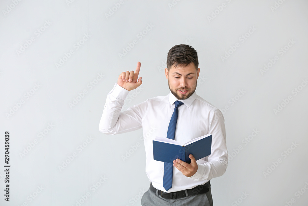 Portrait of handsome businessman with book and raised index finger on light background Portrait of handsome businessman with book and raised index finger on light background