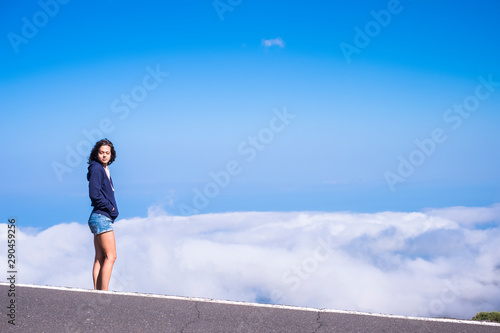 Dreaming and freedom concept with beautiful tall standing young woman with closed eyes and clouds and blue sky in background