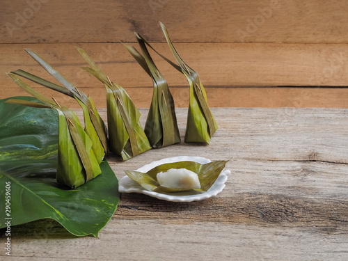 Khanom sot sai or khanom sai sai in white dish on wood background, Thai dessert with a sweet filling made up of coconut and palm sugar filling is covered with steamed flour mixed with coconut cream.