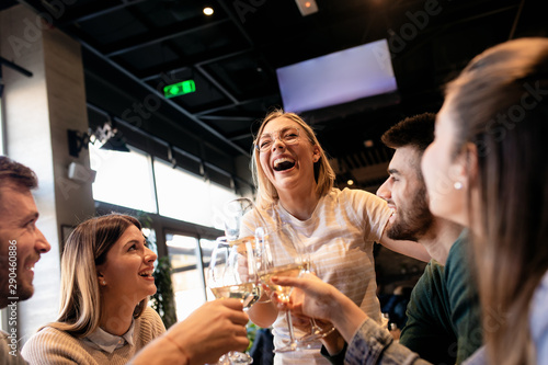 Group of young friends having fun in restaurant, talking and laughing while dining at table.