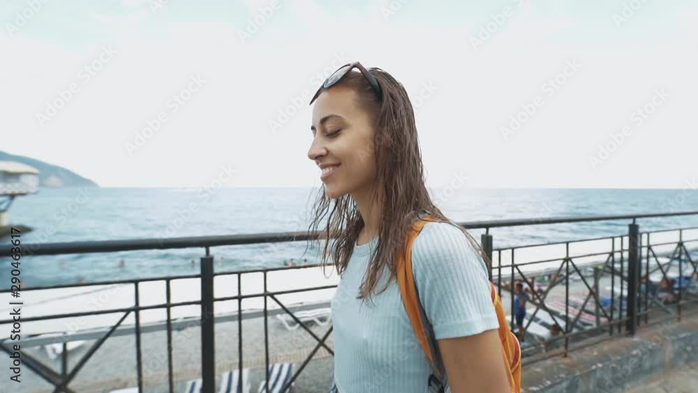 outside portrait of Beautiful young sexy woman in casual wear and small backpack walking along bay at seaside, against a blue sea. portrait luxury resort carefree tourism destination female sexy outside portrait of Beautiful young sexy woman in casual wear and small backpack walking along bay at seaside, against a blue sea. portrait luxury resort carefree tourism destination female sexy