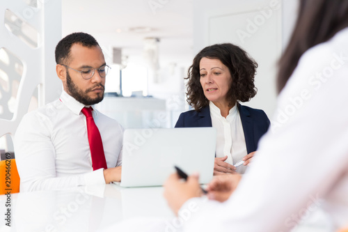 Customer consulting professionals. Business man and woman sitting at conference table with open laptop and talking to colleague sitting opposite. Expertise concept