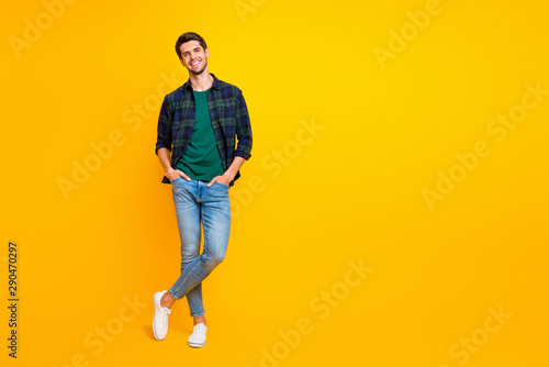 Full length body size photo of cheerful charming cute handsome man posing in front of camera with hands in pockets isolated over vivid color background