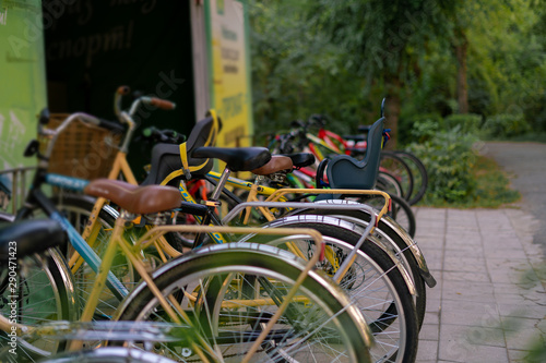 row of many bicycles parked on the public city rent in the park on a summer season, weekend activitiy.