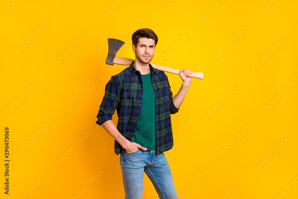 Photo of serious guy looking without smile ready to use big ax which hold in strong arms wear casual plaid shirt isolated yellow color background Photo of serious guy looking without smile ready to use big ax which hold in strong arms wear casual plaid shirt isolated yellow color background