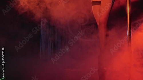 beautiful girl dances striptease on a pylon in a strip club for a client