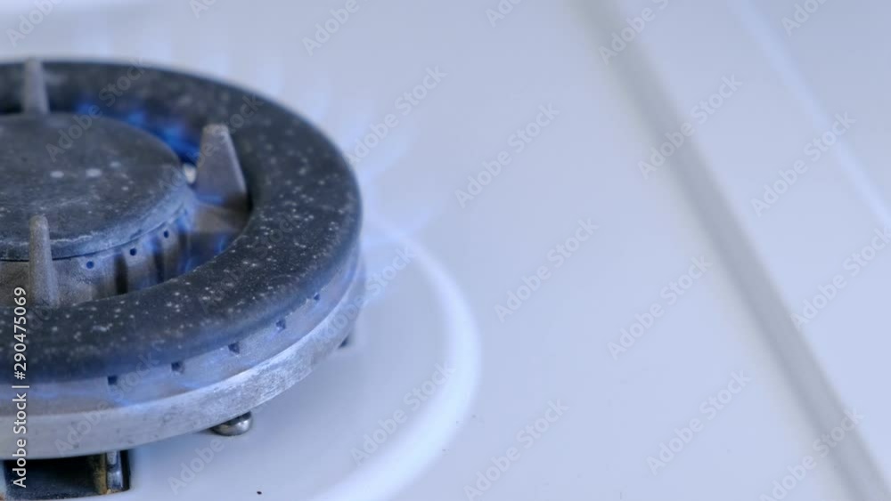 Gas burning from a kitchen gas stove in big gas burner. Half of gas burner in left side. Close-up view. Gas burning from a kitchen gas stove in big gas burner. Half of gas burner in left side. Close-up view.