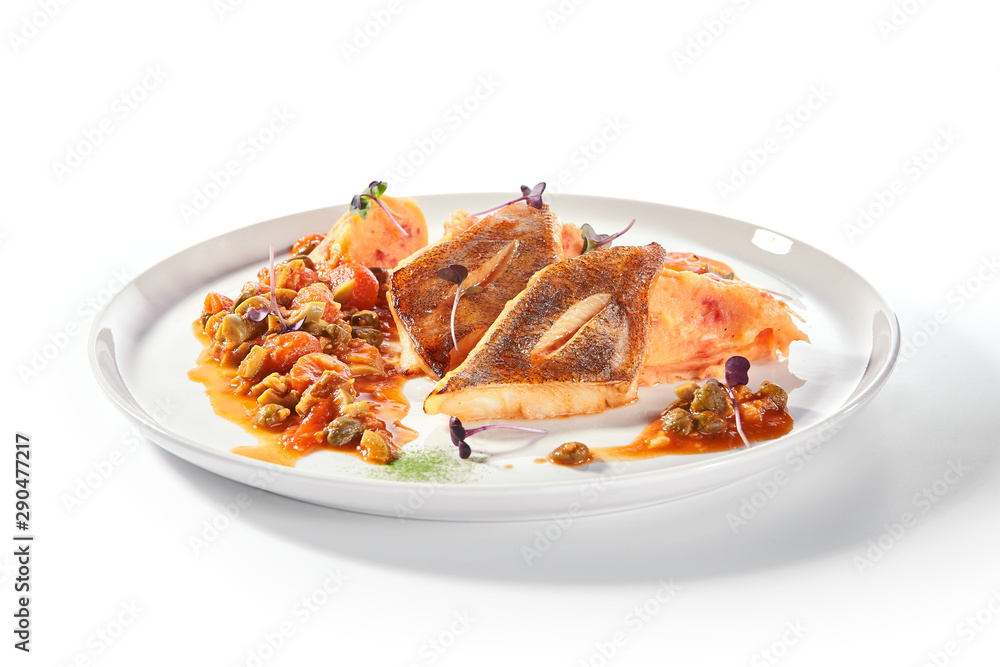 Pike perch or zander fillet with a side dish of tomatoes and capers served on a round platter Pike perch or zander fillet with a side dish of tomatoes and capers served on a round platter