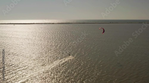 Aerial view of kitesurfer gliding and jumping across ocean