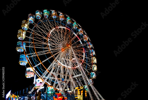 Giant Ferris Wheel with well illuminated cabins and decorated with colorful lights during night, is up for the entertainment, in a local festival in Goa during summers.