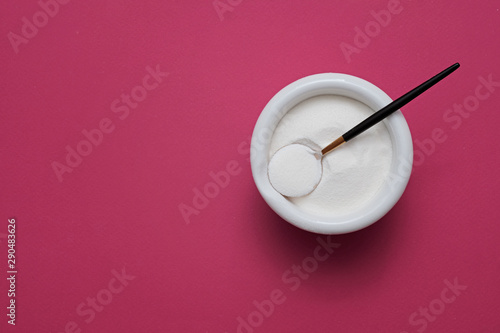 collagen protein powder in a bowl with a modern spoon on purple background