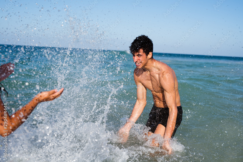 Young man splashing a girl with water