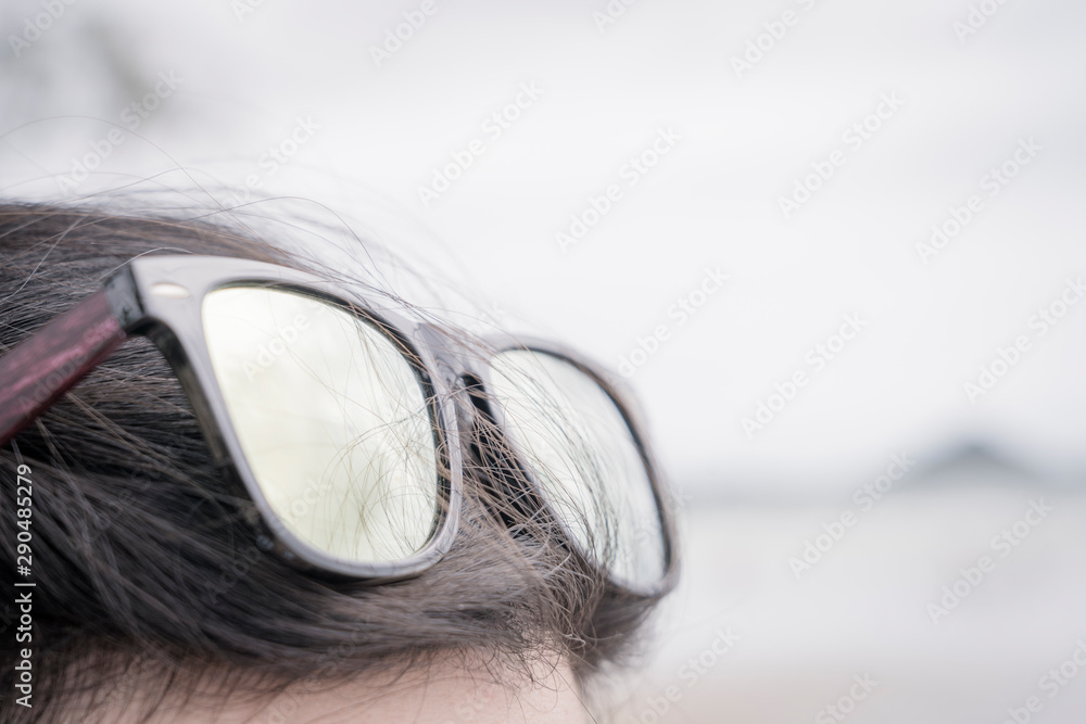 sunglasses over head enjoying summer sun , light grey background