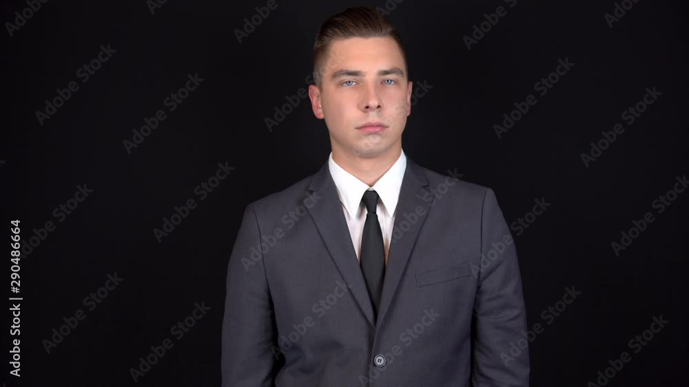 Young businessman shakes his head denying. Man in a black suit on a black background Young businessman shakes his head denying. Man in a black suit on a black background