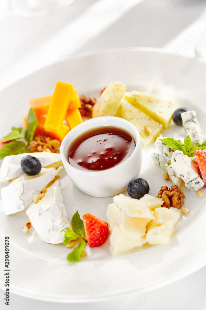 Gourmet, restaurant, delicious dinner food - close up of cheese plate with honey dip and fresh berries Gourmet, restaurant, delicious dinner food - close up of cheese plate with honey dip and fresh berries