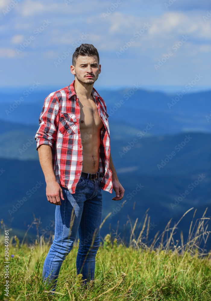 cowboy in hat outdoor. sexy macho man in checkered shirt. countryside concept. farmer on rancho. man on mountain landscape. camping and hiking. travelling adventure. hipster fashion