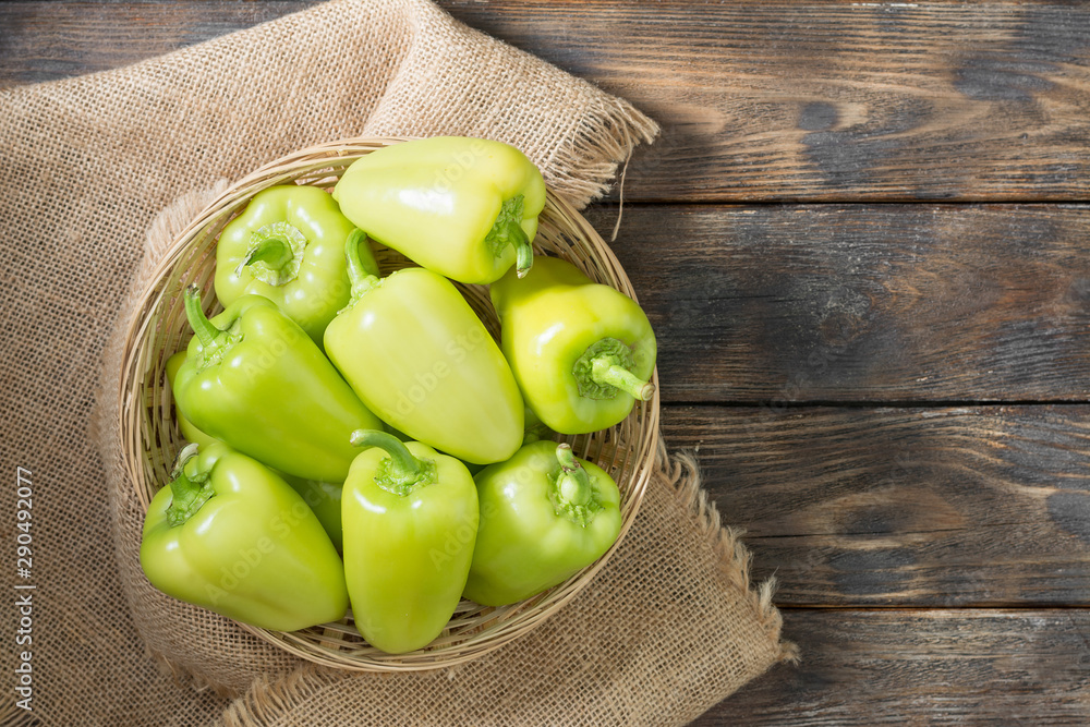 Green bell peppers in a basket on a wooden table. rustic style. Top view