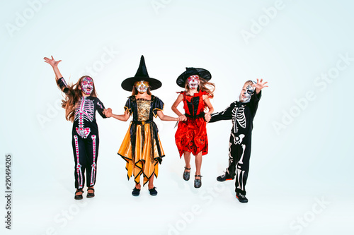 Kids or teens like witches and vampires with bones and glitter on white background. Caucasian models looks scary and playful. Halloween, black friday, sales, autumn holidays concept. The night of fear