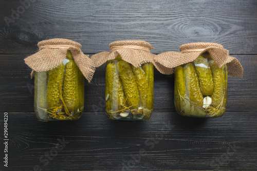 Canned vegetables cucumber in glass jars on woodeb dark board. View from above. Homemade harvest fall preparations. Homework and traditions. photo