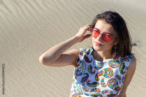 A beautiful young girl sitting on the sand in the desert, sand dunes