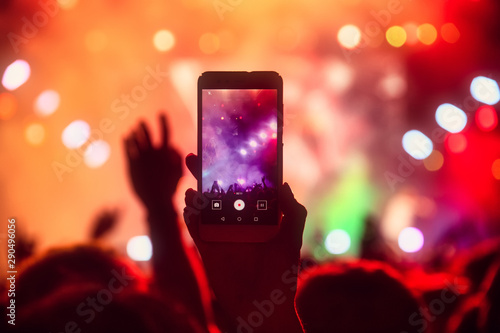 People taking photographs with touch smart phone during a music entertainment public concert