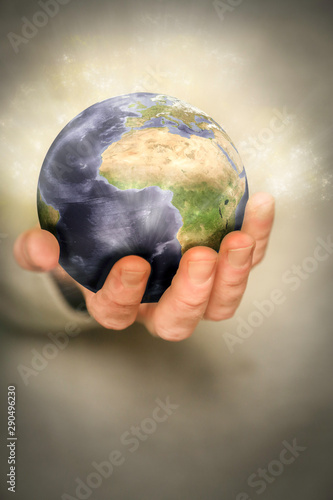 Hand holding the earth, with atmospheric glow around the planet