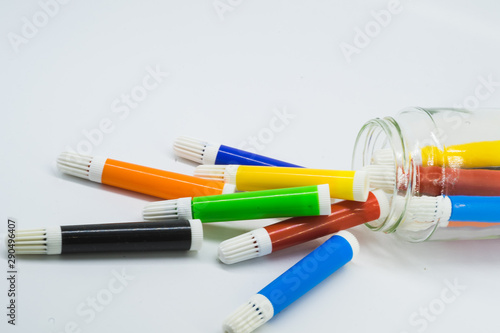 Colourful school supplies, colourful stationery markers in a transparent jar  on white background - space for caption