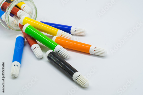 Colourful school supplies, colourful stationery markers in a transparent jar  on white background - space for caption