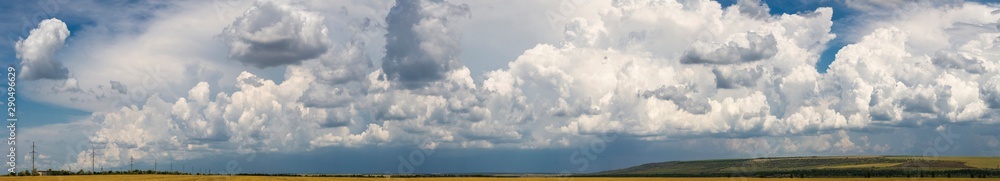 Wheat fields before the rain. Cumuliform cloudscape on blue sky. The terrain in southern Europe. Fantastic skies on the planet earth. The sun is hidden. Panorama. Wheat fields before the rain. Cumuliform cloudscape on blue sky. The terrain in southern Europe. Fantastic skies on the planet earth. The sun is hidden. Panorama.